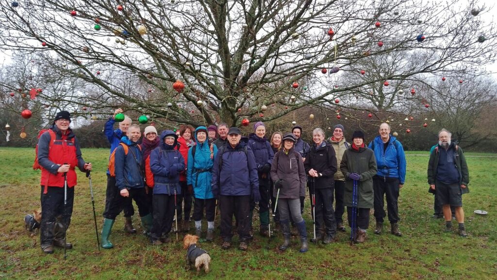 Walkers pose beside a tree decorated with baubles at Widmer End
